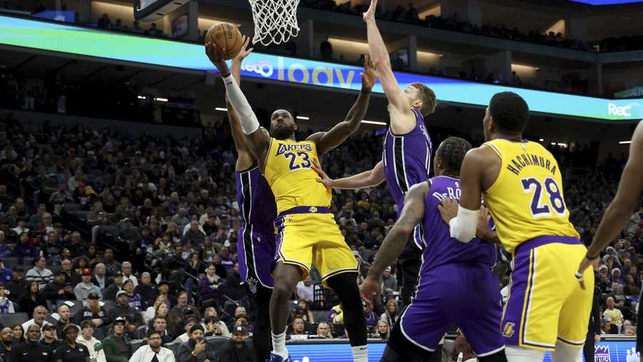 Los Angeles Lakers forward LeBron James (23) shoots against Sacramento Kings center Domantas Sabonis, center top right, during the first half of an NBA basketball game in Sacramento, Calif., Thursday, Dec. 19, 2024. (AP Photo/Jed Jacobsohn)